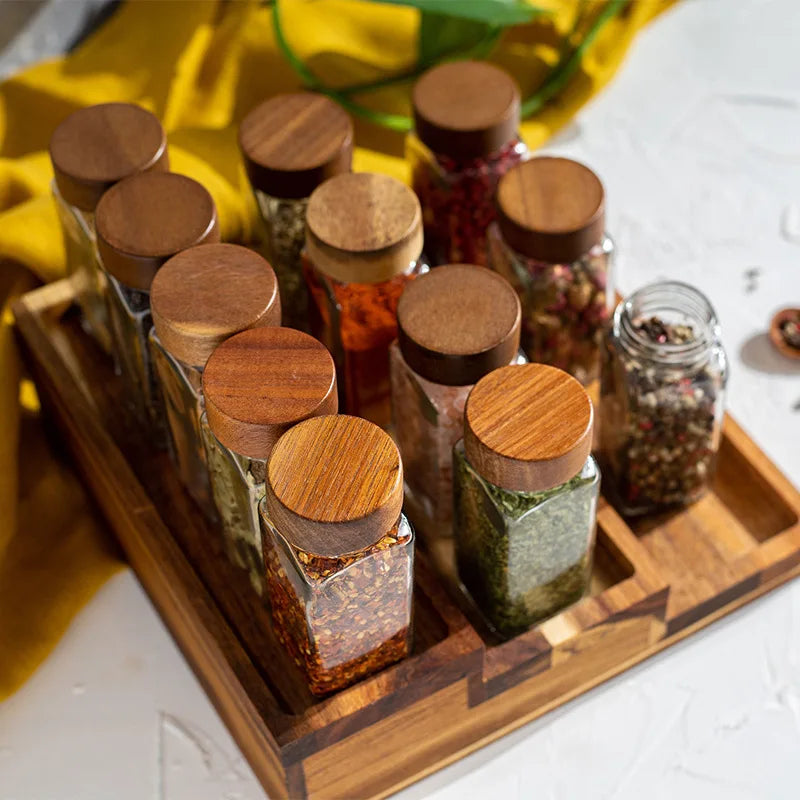 6-Piece Acacia Wood Glass Spice Jars Set. These elegant square glass jars are perfect for storing your favorite spices, herbs, and seasonings, adding a touch of sophistication to your culinary space. - Volaia